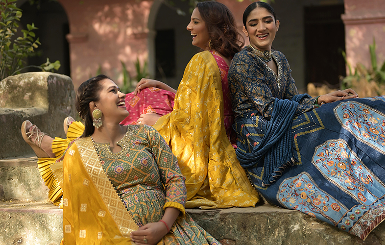 Three beautiful women sitting together wearing latest Anarkali Suits by Kalki Fashion pictured on an outdoor location
