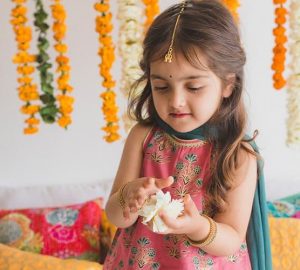 A small girl wearing ethnic dress playing with flowers looking cool and comfortable